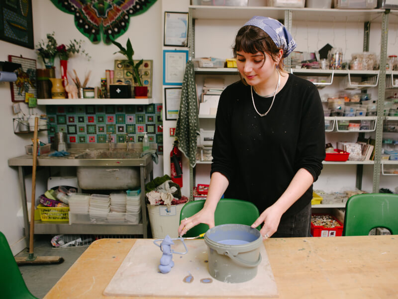 Woman dipping ceramic in pot of paint